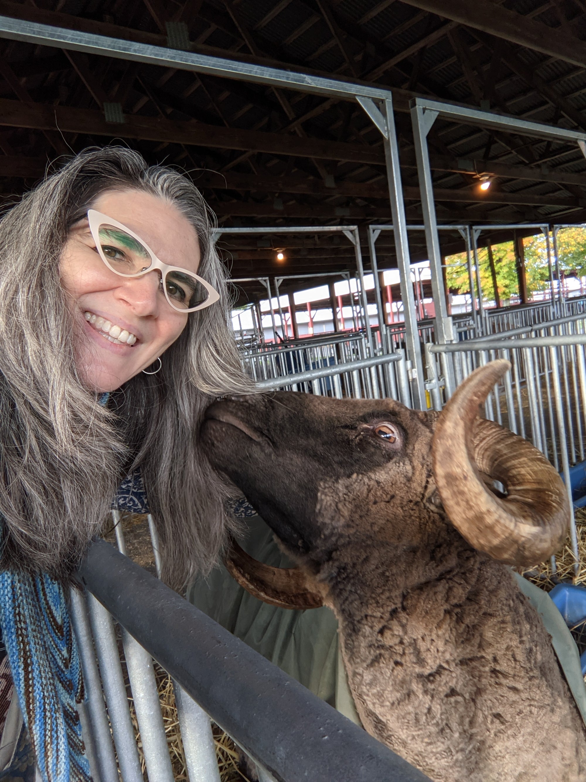 
          
            Natalia smiling with a sheep nuzzling her hair
          
        