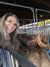 
          
            Natalia smiling with a sheep nuzzling her hair
          
        