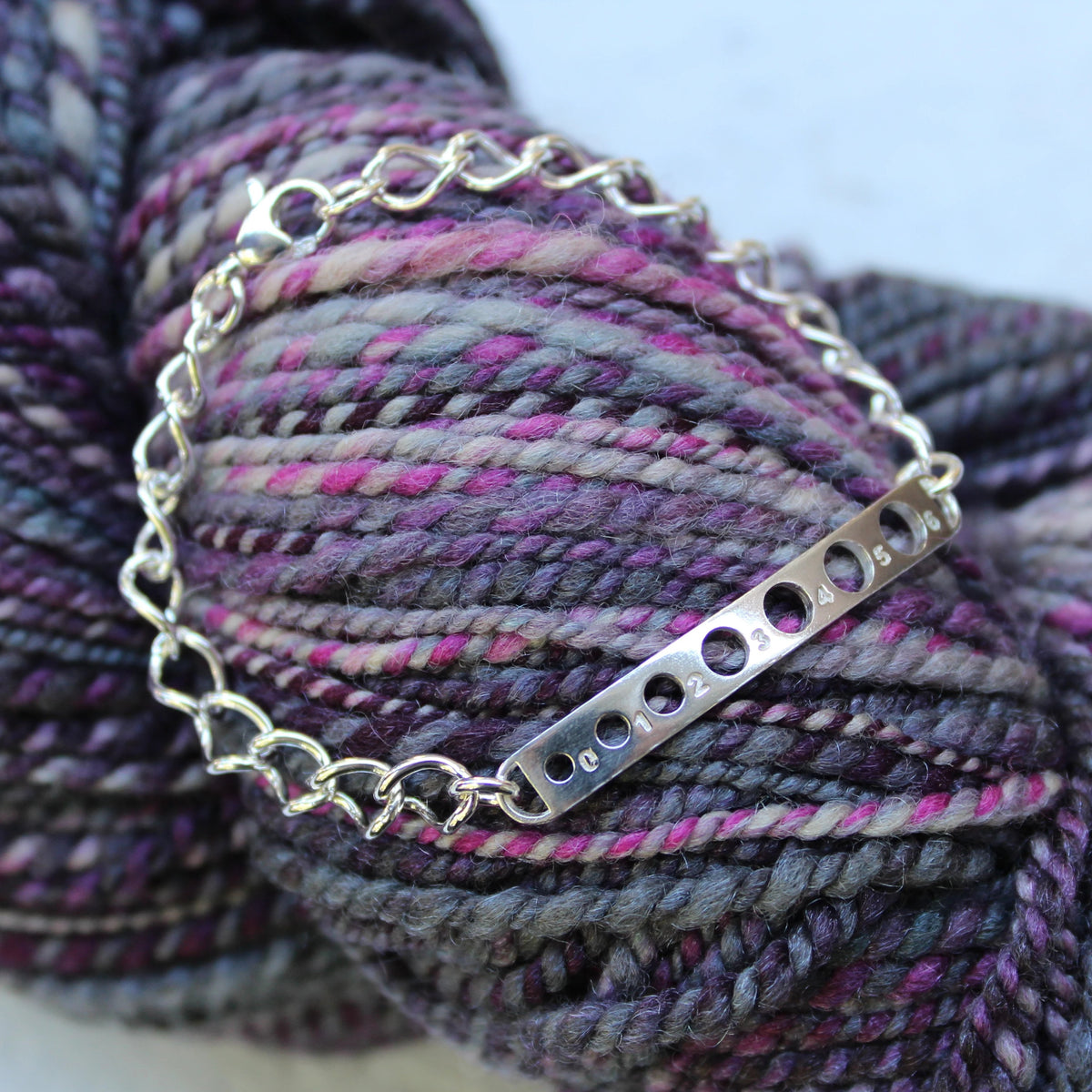 silver plate bracelet with knitting needle gauge holes cut out of the plate