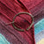 Sterling silver penannular shawl in with a hammered surface texture, pinning a shawl in reds, purples, and blues, shut.